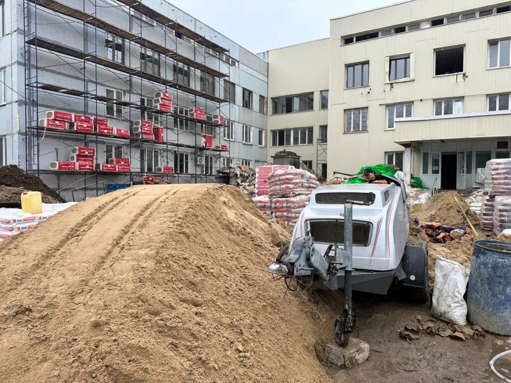 Оборудование для механизированной стяжки: бетононасос, песок и мешки с цементом у здания
